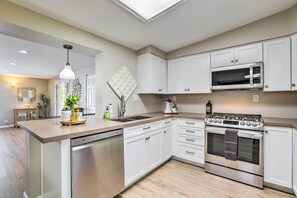 A modern kitchen with white cabinetry, a built-in microwave, a stainless steel stove, and a dishwasher. - 7 Mi to Downtown Phoenix: Home w/ Pool & Foosball! (Phoenix)
