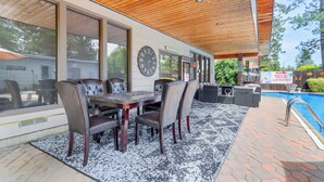 Un patio exterior con una mesa y sillas de comedor, una piscina y un techo de madera.