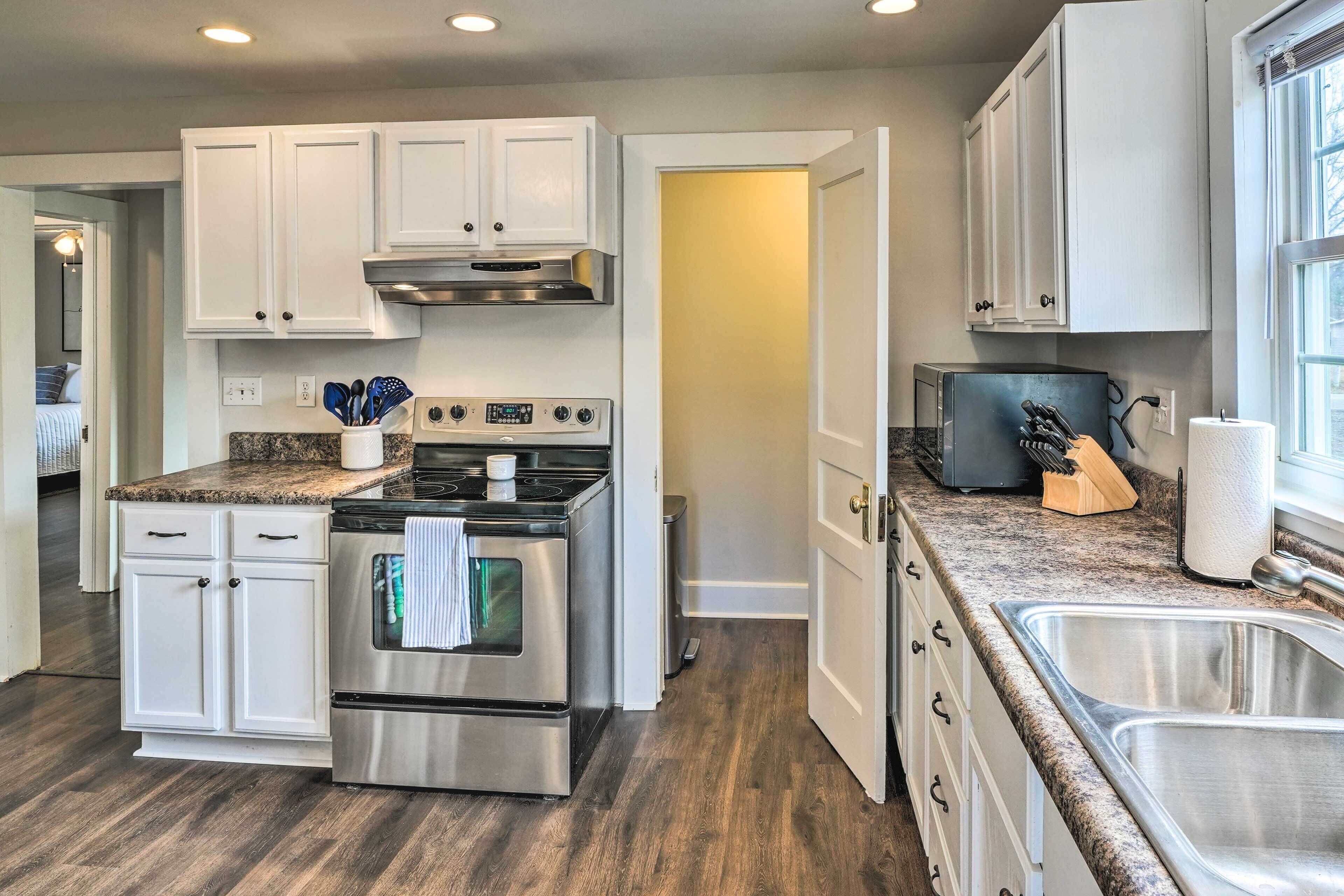 A modern kitchen with white cabinets, stainless steel appliances, granite countertops, and a large window providing natural light.