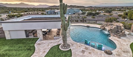A modern house with a swimming pool, a cactus, and a view of mountains.