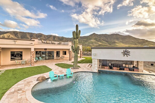Relax by the pool surrounded by a mountain view and a beautifully maintained patio with a cactus centerpiece.