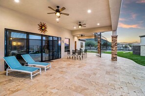 Relax in style on this expansive patio, complete with lounge chairs, a dining table, and ceiling fans for comfort.