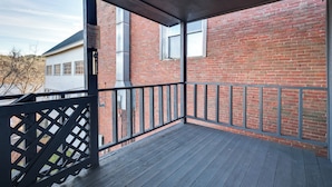 A covered porch with a brick wall and a wooden deck. - Downtown Hallowell Retreat w/ Water Views! (Hallowell)