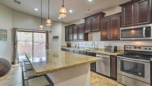 A modern kitchen with granite countertops, stainless steel appliances, and dark wood cabinets.