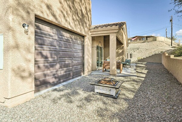 Una propiedad residencial con garaje, zona de estar exterior y una chimenea.