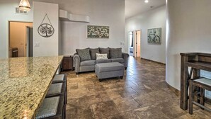 A spacious living area with a large kitchen island, a grey sofa, and a dining table.