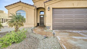 A stucco building with a large garage door, a curved driveway, and a palm tree.