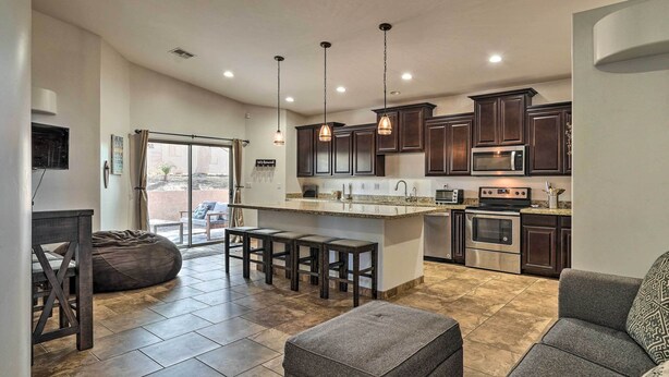 A modern kitchen with dark cabinets, a central island, and pendant lighting.