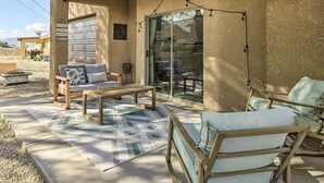 A covered patio with a sofa, a wooden table, and two chairs.