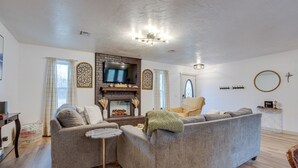 A living room with a fireplace, grey sofas, a TV, and a chandelier. - Chandler Vacation Rental on Route 66, Near Casino (Chandler)