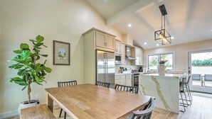 A modern kitchen with a central island, wooden dining table, and chairs. - Luxury Scottsdale Vacation Rental w/ Patio! (Scottsdale)