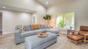 A modern living room with a sectional sofa, a brown leather ottoman, and a small wooden side table. - Luxury Scottsdale Vacation Rental w/ Patio! (Scottsdale)