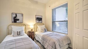 Une chambre avec deux lits, chacun doté d’une tête de lit, d’une table de chevet et d’une lampe. Deux œuvres d’art sont accrochées au mur au-dessus des lits.