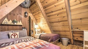 A cozy attic bedroom with a sloped ceiling, wooden beams, a bed with a galaxy-themed bedspread, a small shelf with decorative items, and a wall-mounted lantern. - 8 Mi to Heavenly Mtn Resort! Hot Tub Hideaway (South Lake Tahoe)
