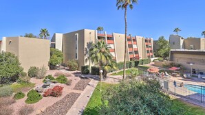 A hotel courtyard with a swimming pool, palm trees, and a landscaped garden.