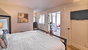 Un dormitorio con una cama grande, un escritorio y una silla. Hay una puerta que da a un balcón con vistas al exterior.