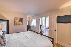 Une chambre avec un grand lit, un bureau et une chaise. Une porte donne sur un balcon d’où l’on peut admirer la vue.