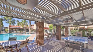 An outdoor pool area with a table tennis table, lounge chairs, and a covered seating area with a pergola.