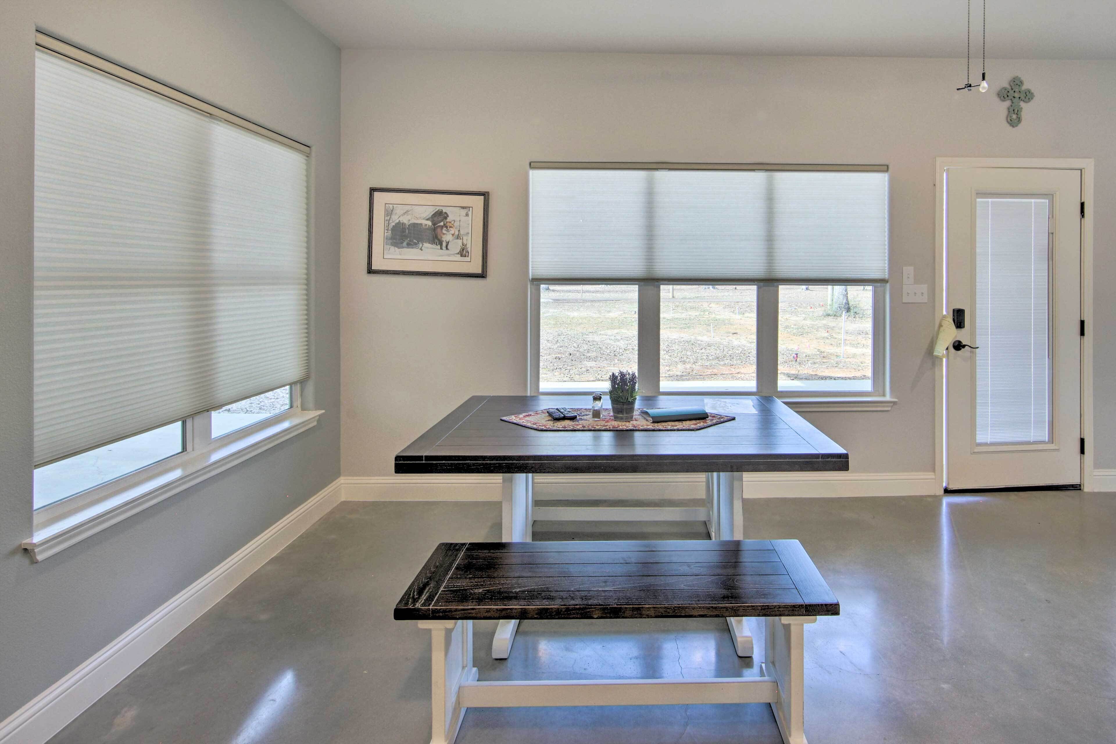 A room with a dark wooden bench, a table with a placemat, and a framed picture on the wall.