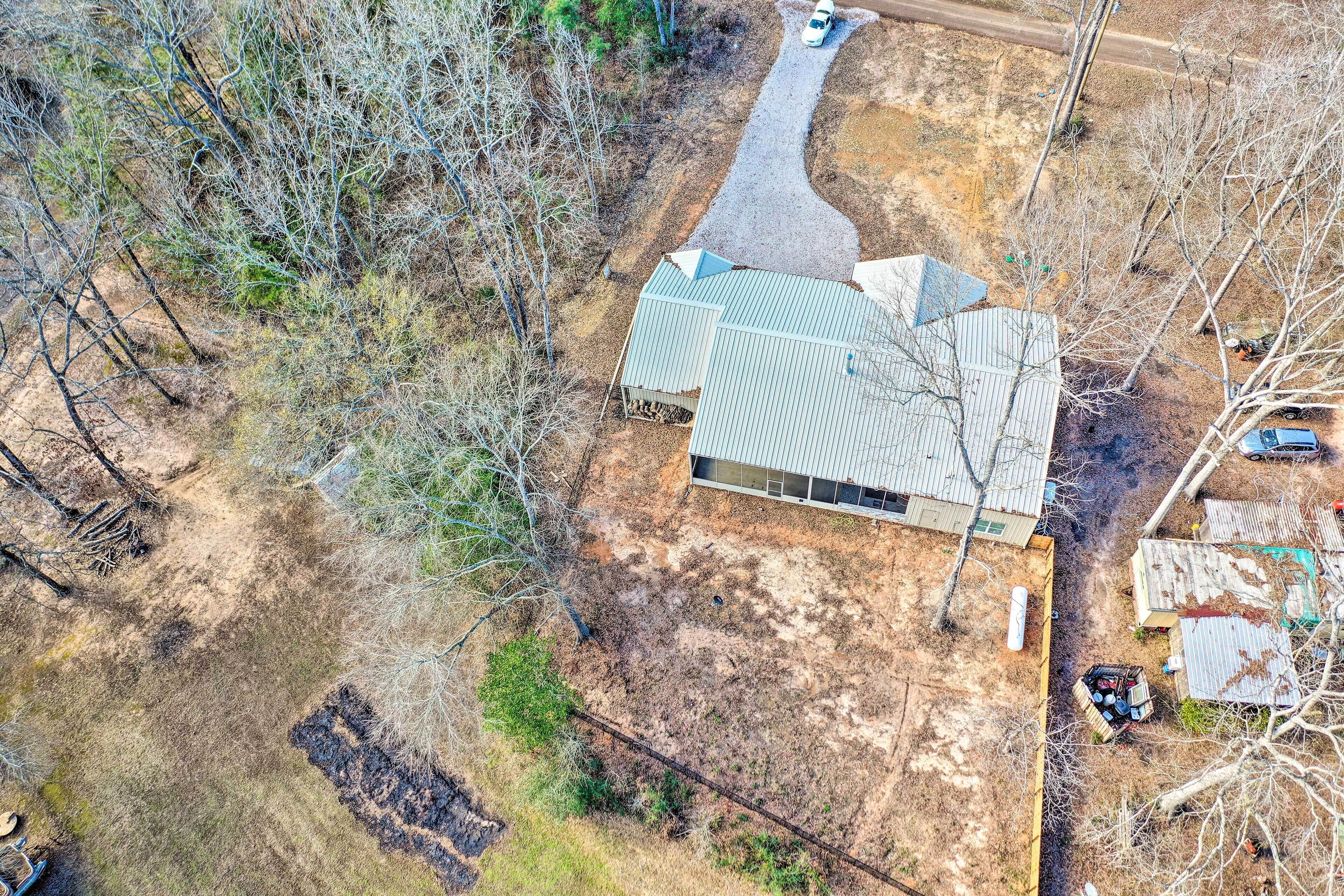 An aerial view of a property with a large house, a driveway, and surrounding trees.