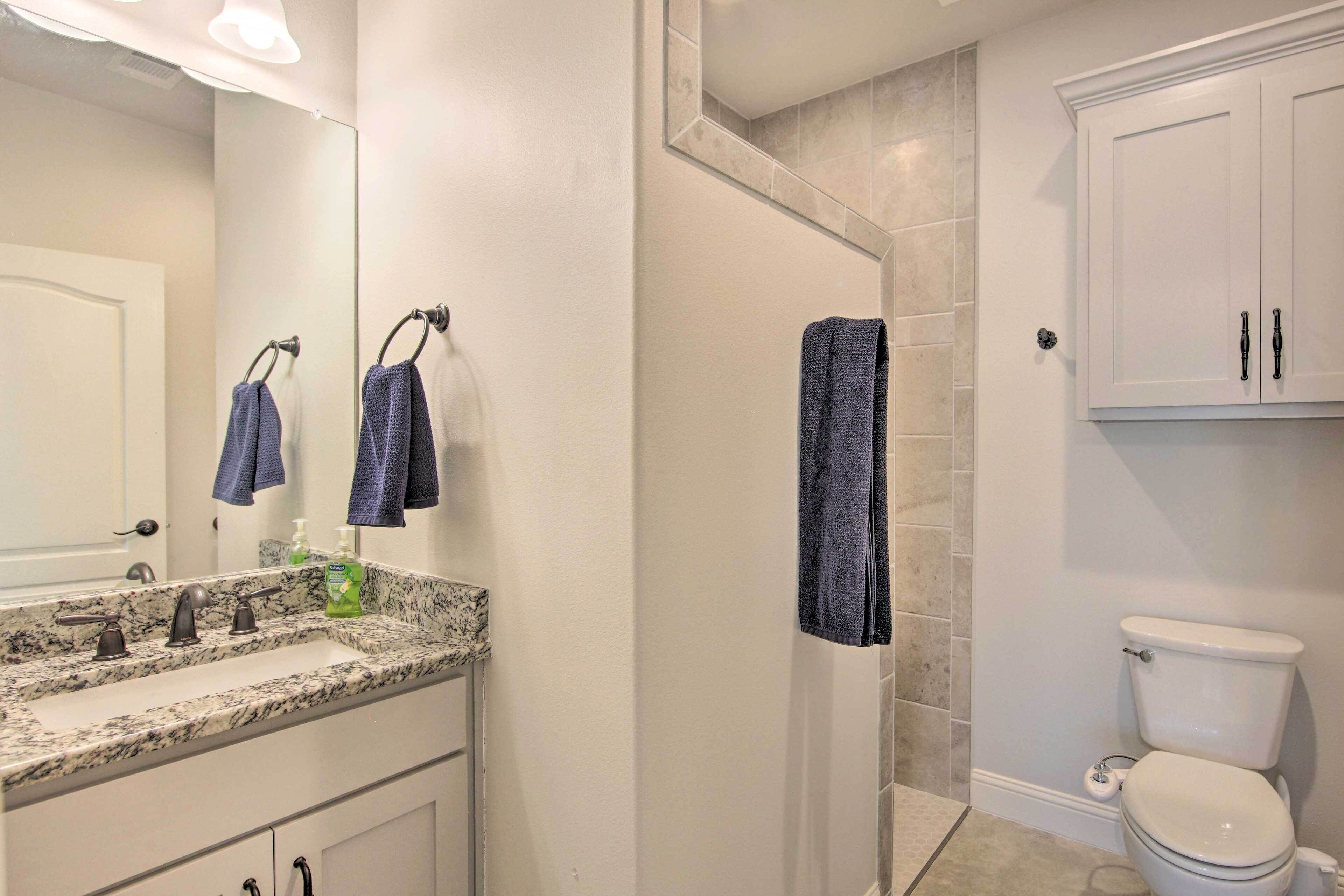 A bathroom with a white toilet, a sink with a marble countertop, and a mirror above the sink.