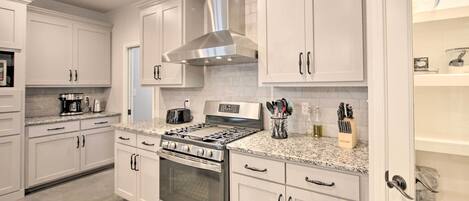A modern kitchen with white cabinetry, stainless steel appliances, and granite countertops.