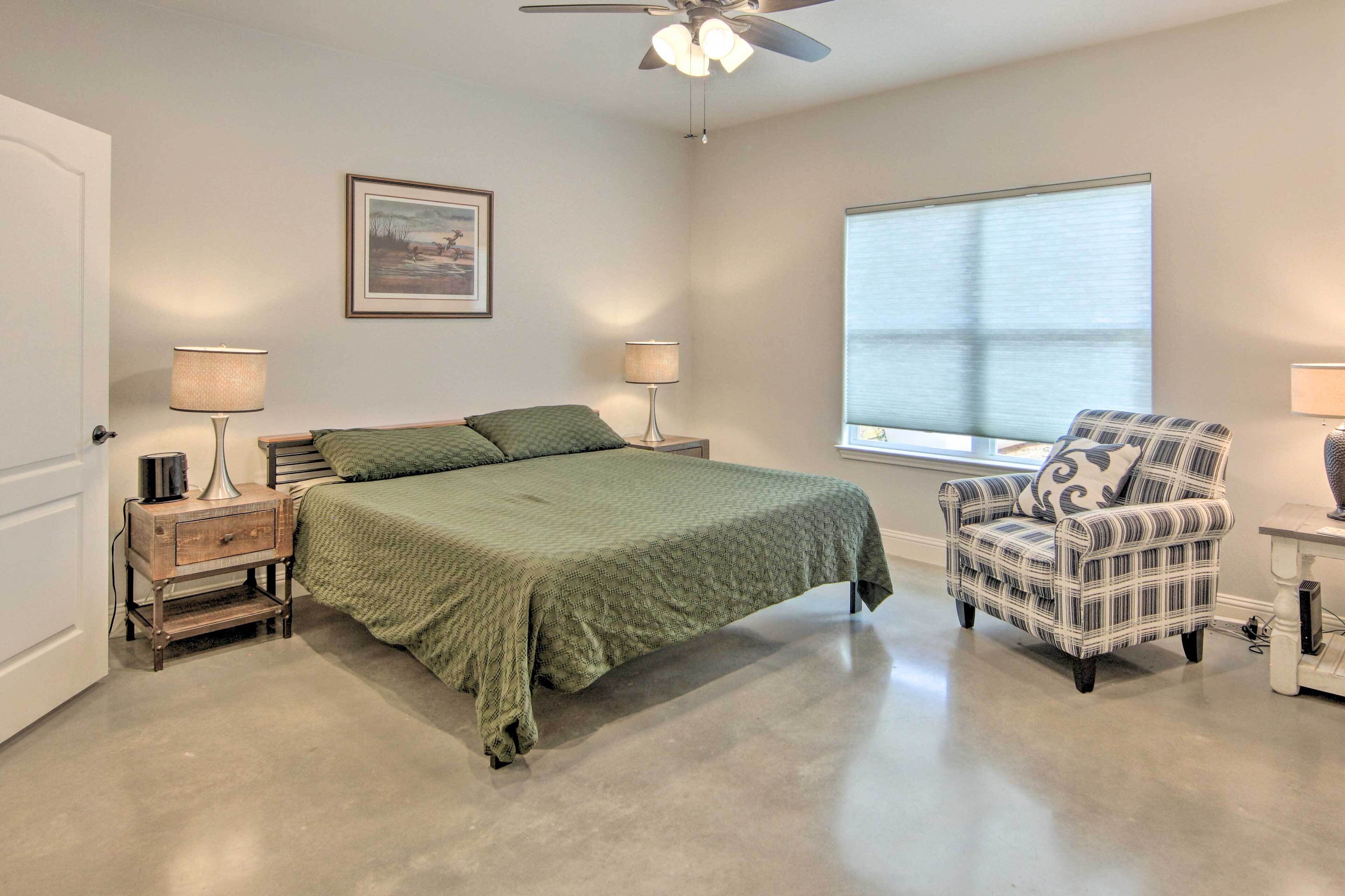A bedroom with a bed, two bedside tables with lamps, a chair, a window, and a ceiling fan.