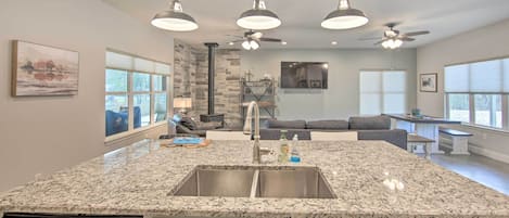 A modern kitchen with granite countertops, stainless steel appliances, pendant lighting, and a built-in island with a sink.
