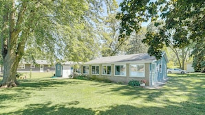 A single-story house with a front porch, surrounded by a well-maintained lawn and large trees. - Riverfront Dixon, Illinois, Vacation Rental! (Dixon)