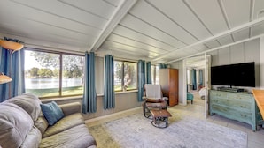 A spacious living room with a large sofa, a wheelchair, a television, and a wooden cabinet. - Riverfront Dixon, Illinois, Vacation Rental! (Dixon)