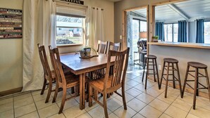 A dining area with a wooden table and chairs, a window with curtains, and a sign on the wall. - Riverfront Dixon, Illinois, Vacation Rental! (Dixon)