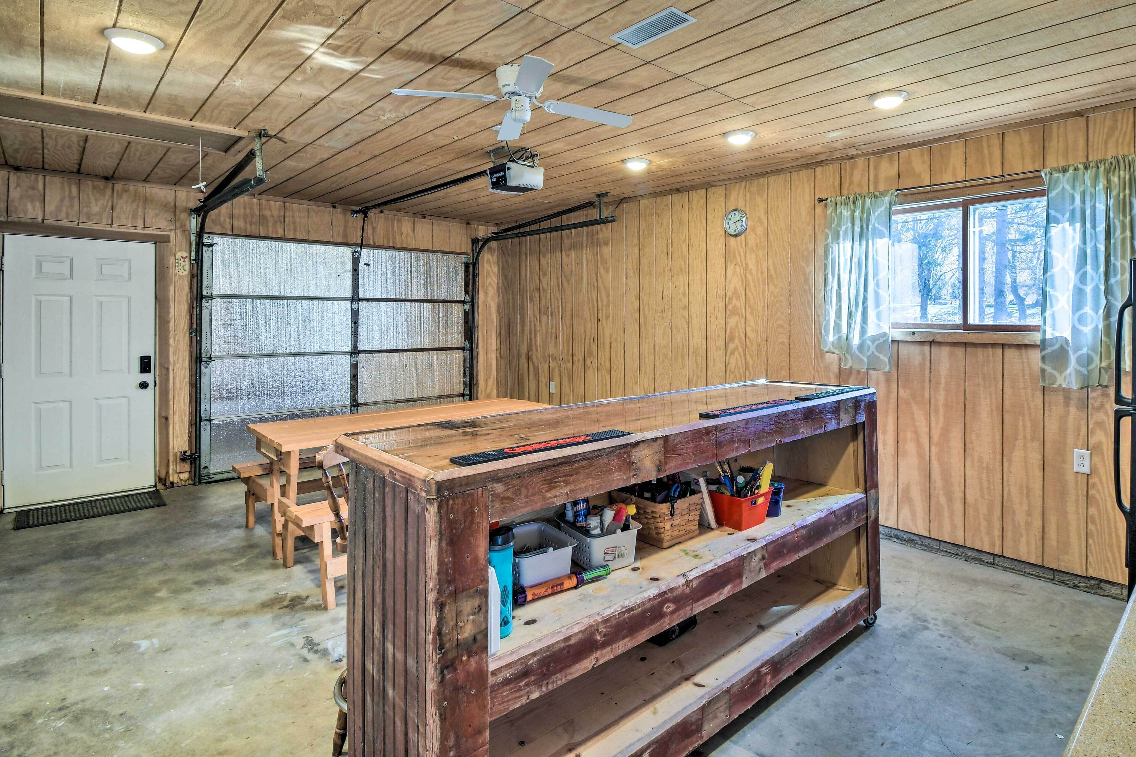 A workshop with a workbench, chairs, and a ceiling fan.