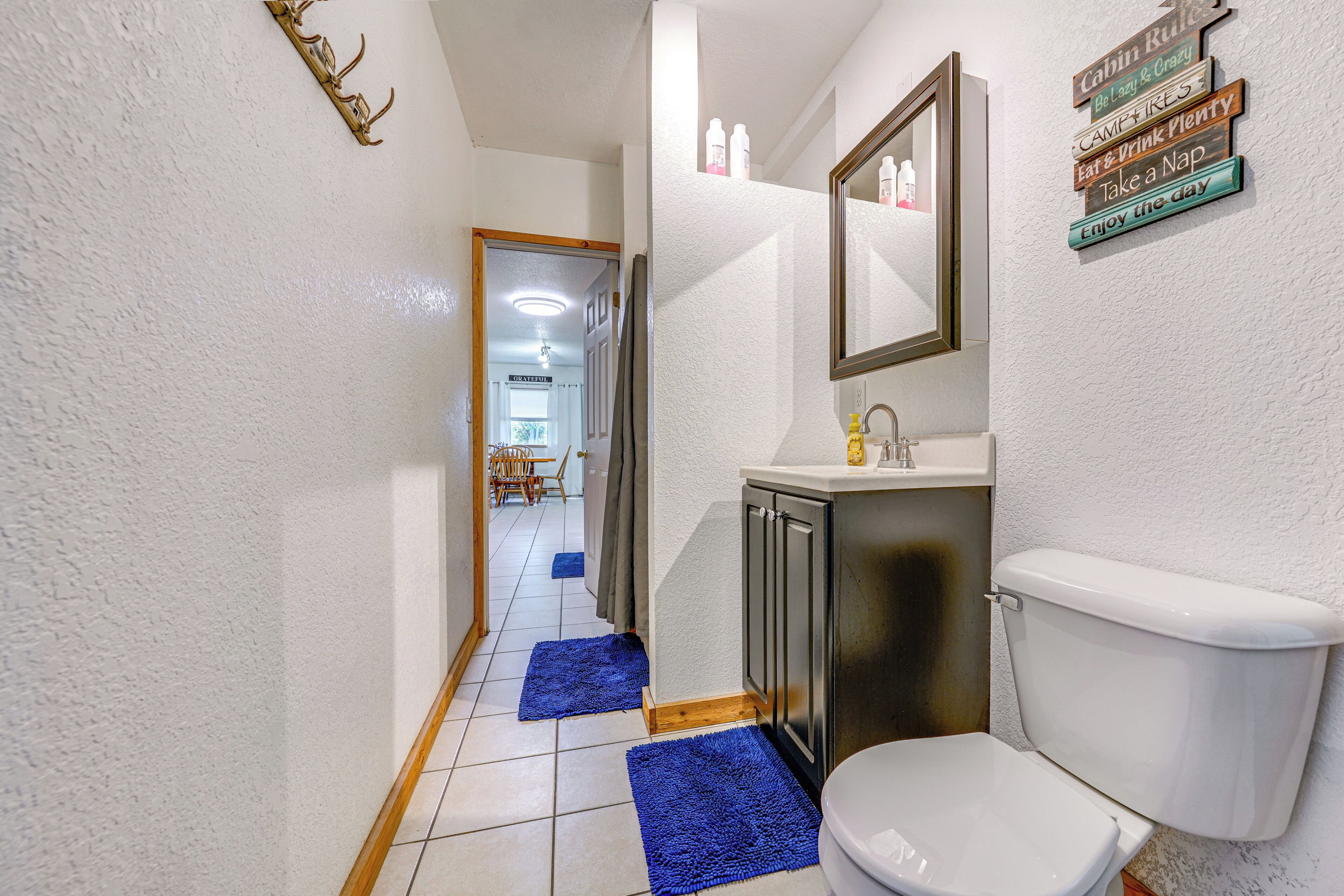 A bathroom with a toilet, sink, mirror, and decorative signs on the wall.