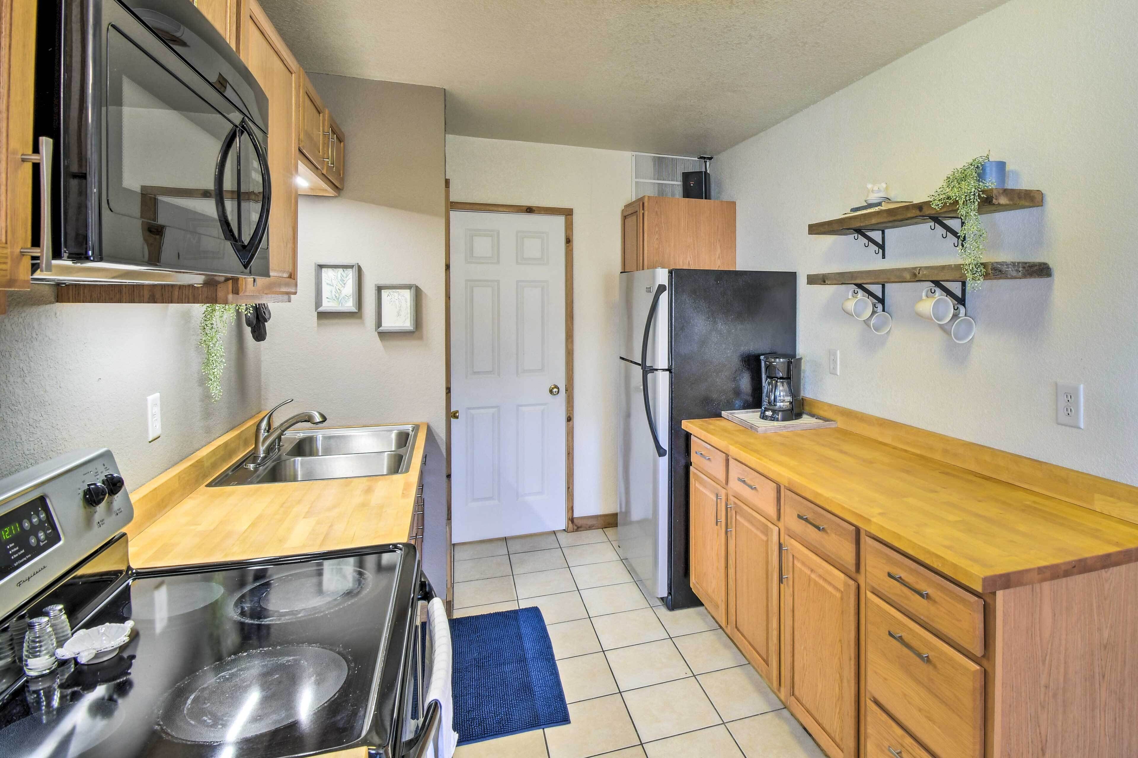A kitchen with wooden cabinets, a stainless steel refrigerator, a microwave, and a stove.