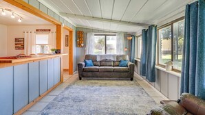 A cozy living area with a wooden bench, a sofa, and a dining table with a sign that reads "GRATEFUL". - Riverfront Dixon, Illinois, Vacation Rental! (Dixon)