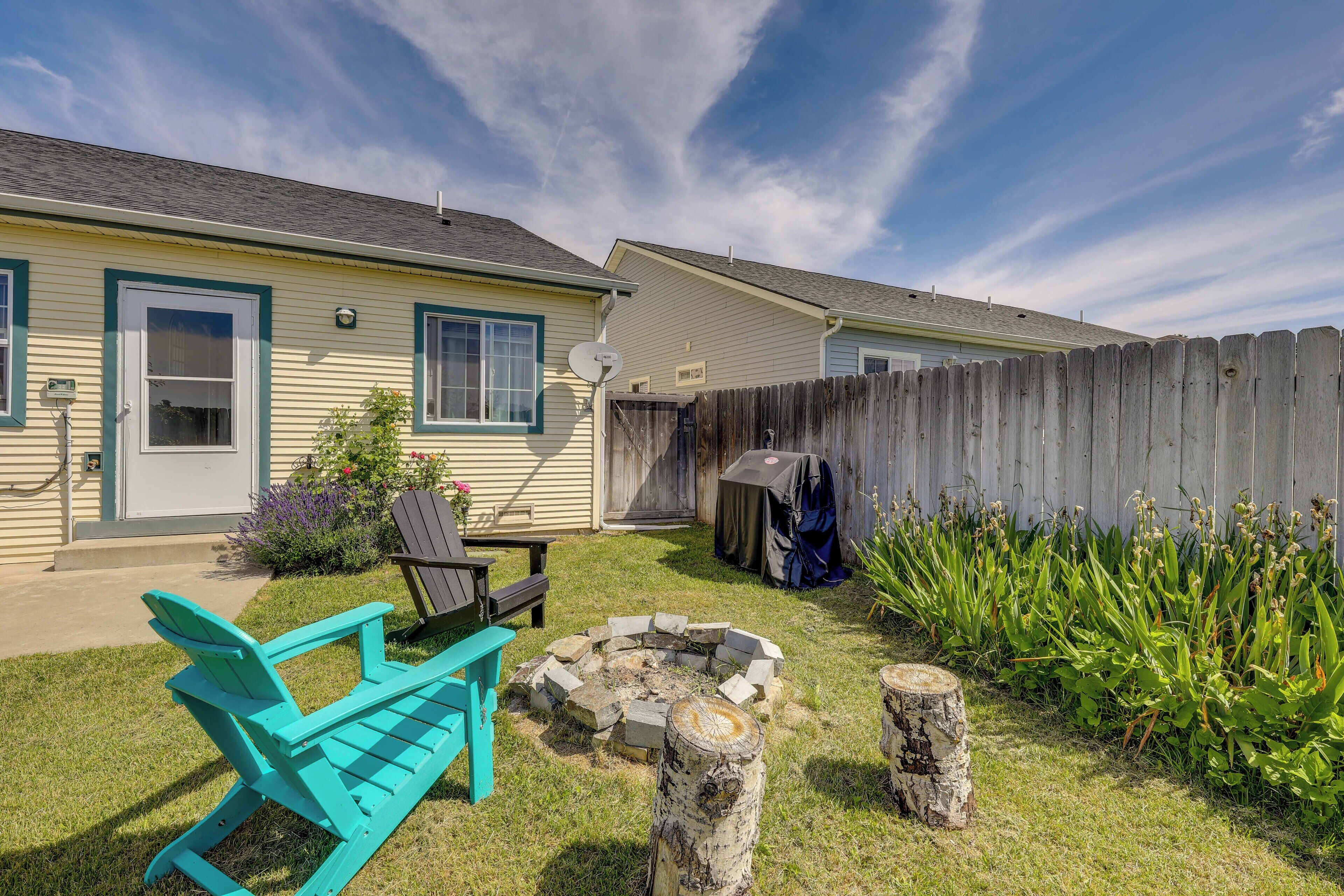 A backyard with a fire pit, a wooden fence, and a house with a door and windows.