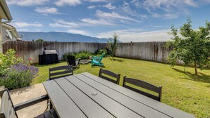 Patio con mesa y sillas de madera, una parrilla y una valla de madera.