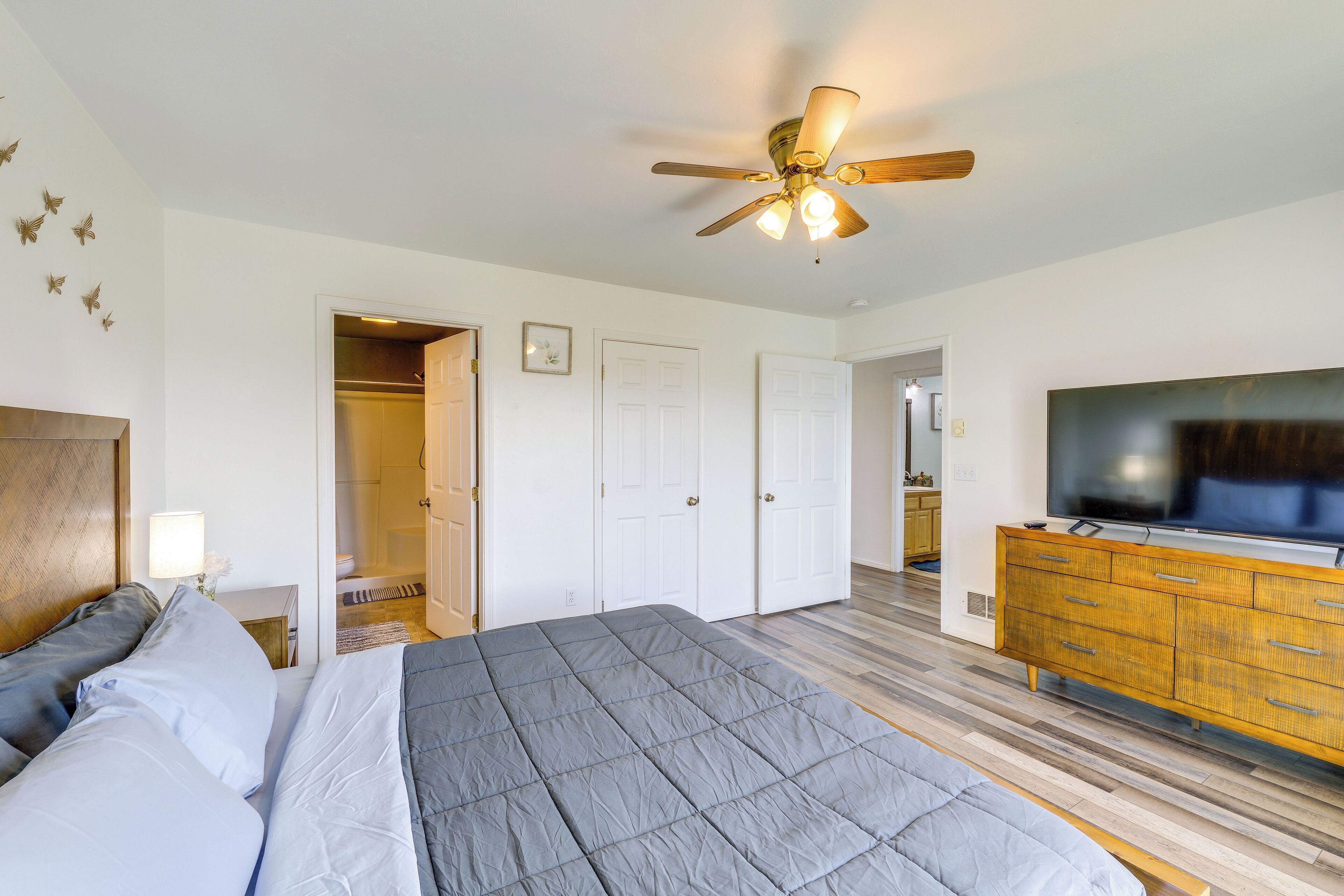 Ein Schlafzimmer mit einem Bett, einem Deckenventilator, einem Kleiderschrank und einem Fernseher.