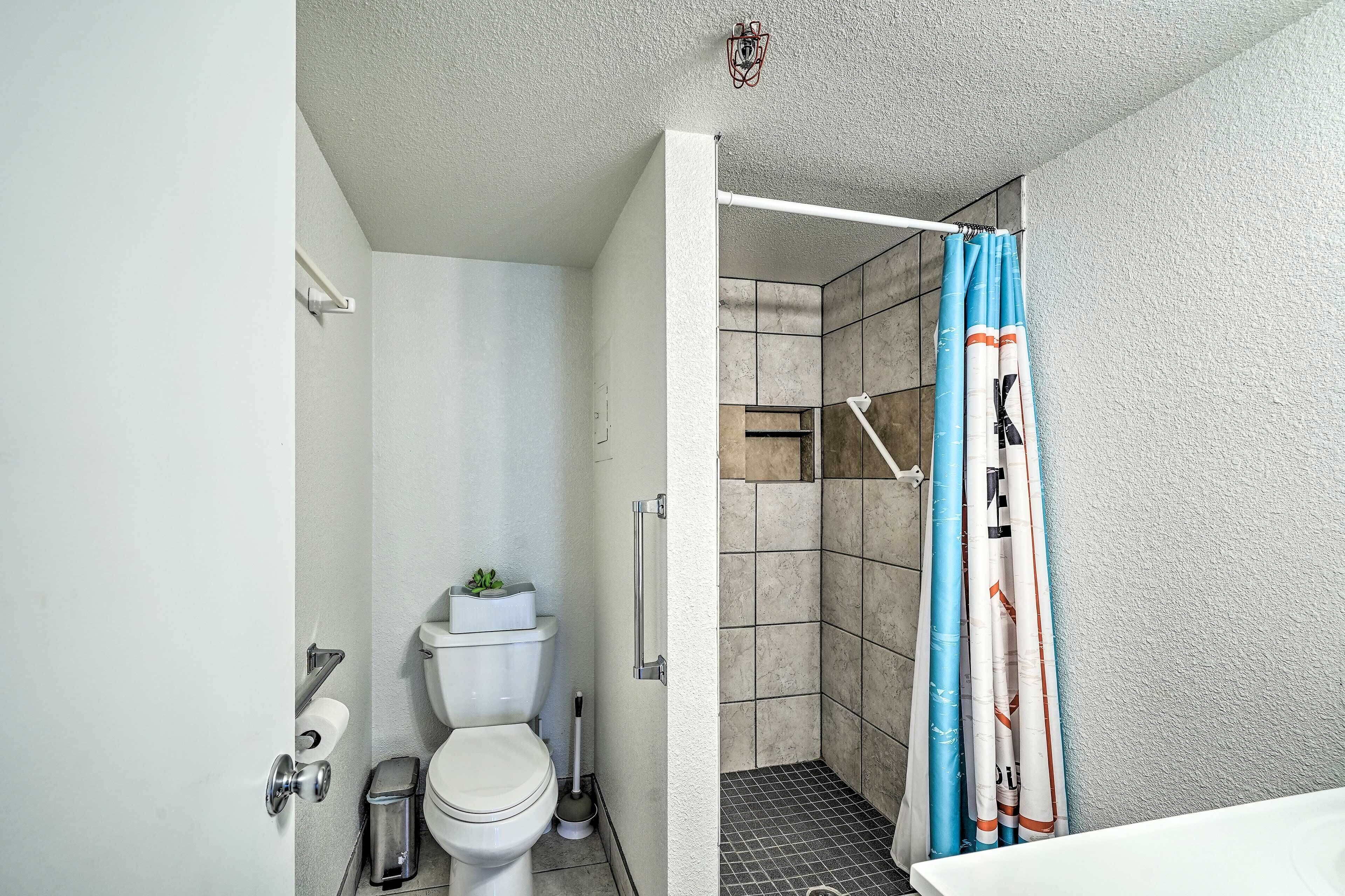 A bathroom with a toilet, a shower with a curtain, and a sink.