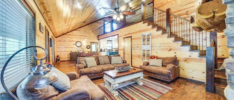 L'intérieur d'un chalet confortable en bois, avec un salon, un escalier et un coin repas.