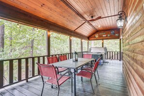 Un espace extérieur abrité, doté d’une terrasse en bois, d’une table avec des chaises et d’un barbecue.