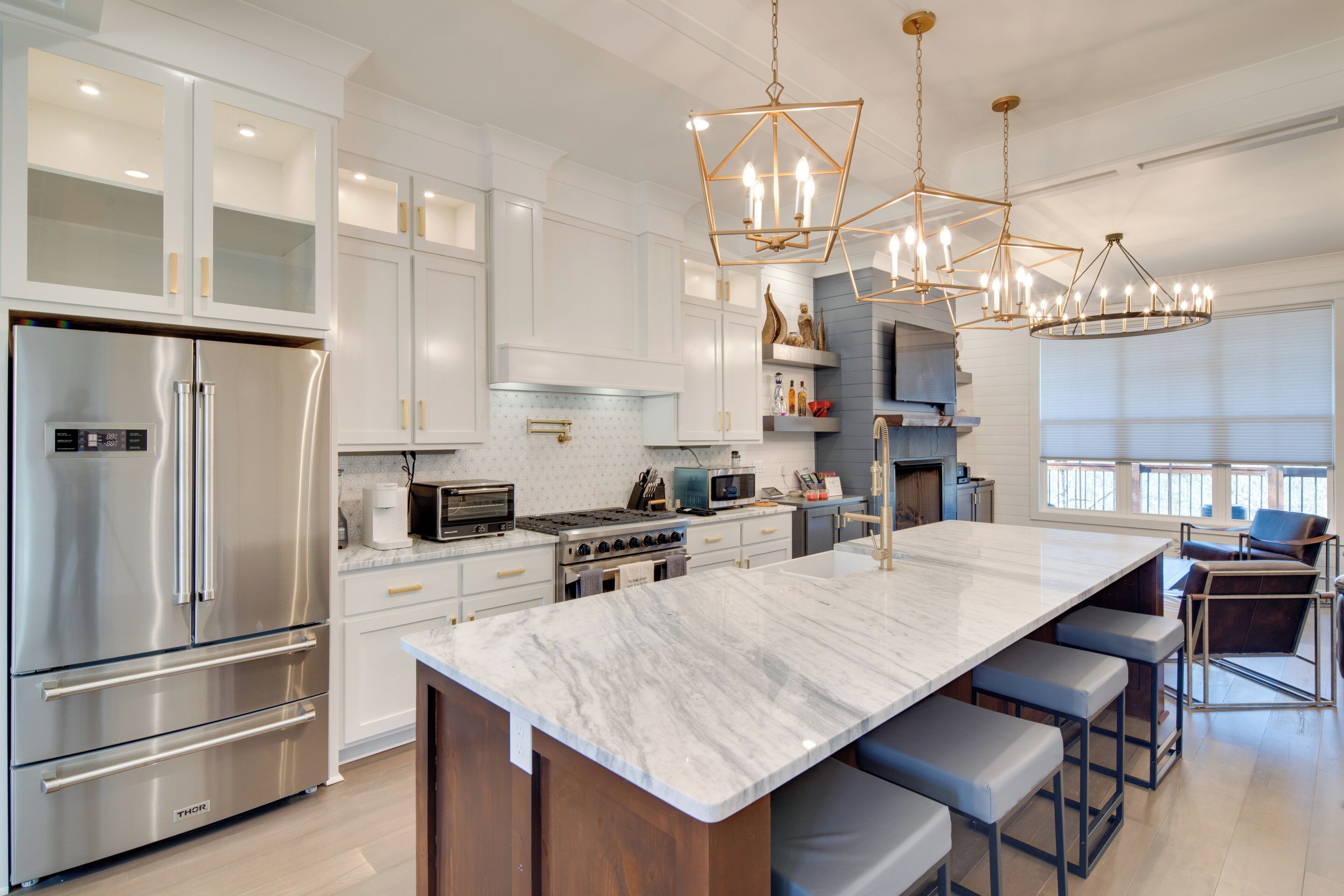 A modern kitchen with stainless steel appliances, a marble island, and pendant lighting.