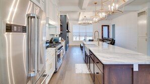 A modern kitchen with stainless steel appliances, a marble island, and pendant lighting. - Fire Pit + Mountain Views! Waynesville Escape (Clyde)