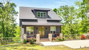 A two-story house with a front porch, stone pillars, and a fenced yard. - Fire Pit + Mountain Views! Waynesville Escape (Clyde)
