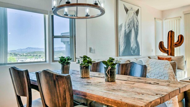 A dining area with a wooden table, chairs, and potted plants. - Pool Access: Mountain-view Condo in Fountain Hills (Fountain Hills)