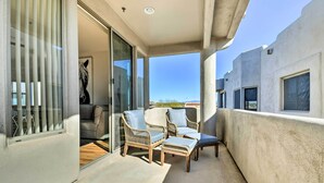 A balcony with wicker furniture, a glass door, and a view of the city. - Pool Access: Mountain-view Condo in Fountain Hills (Fountain Hills)