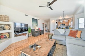 A modern living room with a flat-screen TV, wooden coffee table, grey sofa, and a ceiling fan. - Pool Access: Mountain-view Condo in Fountain Hills (Fountain Hills)