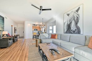 A spacious living room with a large gray sectional sofa, a wooden coffee table, and a ceiling fan. - Pool Access: Mountain-view Condo in Fountain Hills (Fountain Hills)