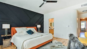 A modern bedroom with a bed, nightstands, a ceiling fan, and a view into the adjacent kitchen. - Pool Access: Mountain-view Condo in Fountain Hills (Fountain Hills)