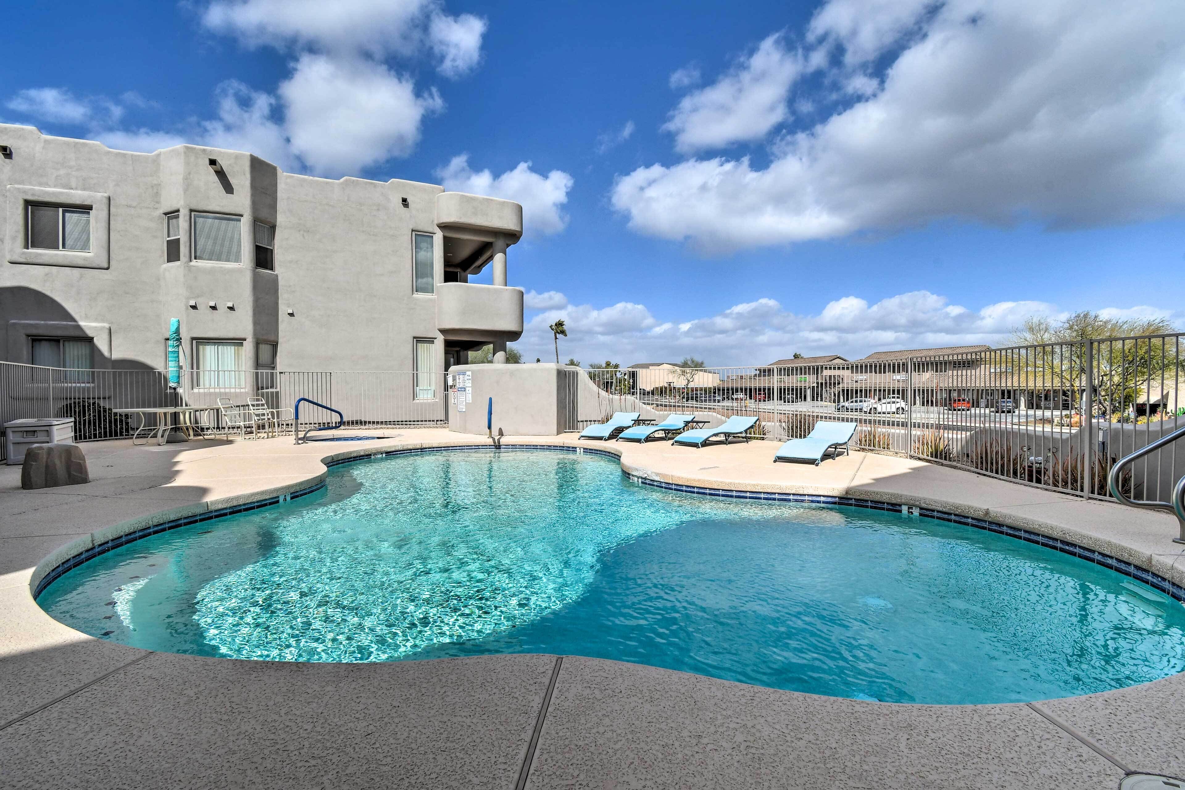 A swimming pool with lounge chairs and a modern building in the background.